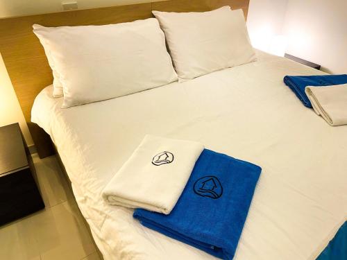 Una cama con sábanas blancas y toallas azules. en Gee9Teen at Fort Chambray, en Mġarr