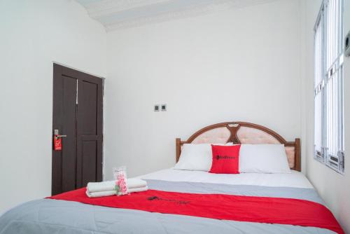 a bedroom with a large bed with red and white pillows at RedDoorz Syariah near Jalan A Yani KM 8 Citraland in Banjarmasin
