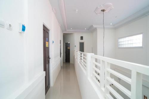 a hallway of a hospital with white walls and a door at RedDoorz Syariah near Jalan A Yani KM 8 Citraland in Banjarmasin