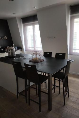 une cuisine avec une table noire, des chaises et des fenêtres dans l'établissement Appartement Cosy et Moderne Puteaux Paris La Defense, à Puteaux