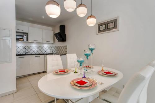 une cuisine et une salle à manger avec une table et des chaises blanches dans l'établissement Appartement Clap d'Or - Welkeys, à Cannes