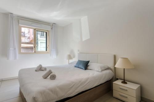 a white bedroom with a large bed and a window at Appartement Clap d'Or - Welkeys in Cannes