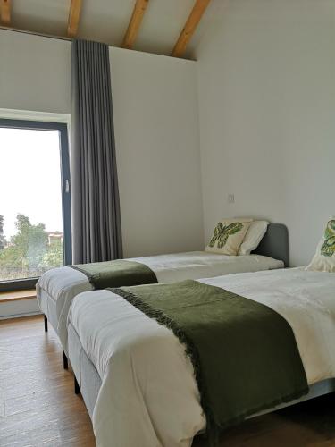 two beds in a room with a window at Casa da Avó Ana Alvão in Bilhó
