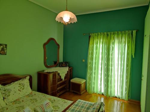 a green bedroom with a bed and a mirror at With a View of Meteora in Diáva