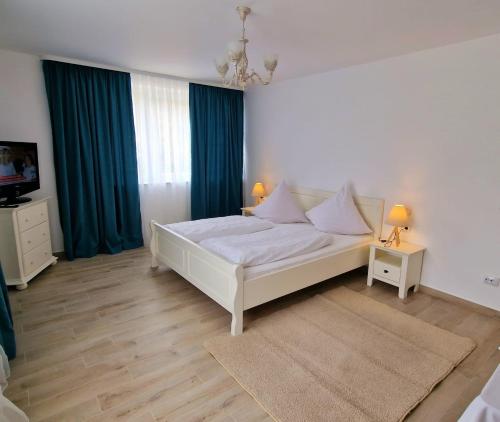 a bedroom with a white bed and blue curtains at Casa Avram in Suceviţa