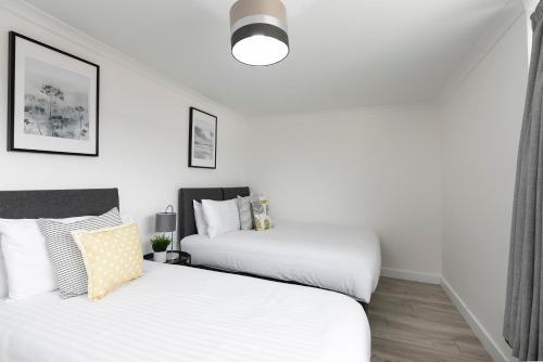 two beds in a room with white walls at Skyvillion - STEVENAGE SPACIOUS & COZY 3Bed House with Parking, Wifi, Garden in Aston End