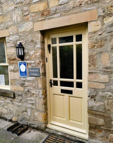 eine Tür zu einem Steingebäude mit einem Schild darauf in der Unterkunft Stonecroft Cottage in Middleham