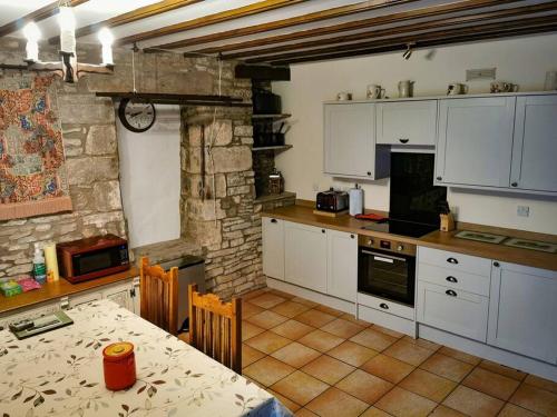 a kitchen with white cabinets and a table in it at Stonecroft Cottage in Middleham