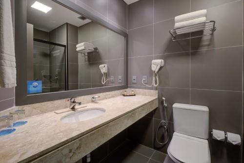 a bathroom with a sink and a mirror and a toilet at Cyan Resort by Atlantica in Itupeva