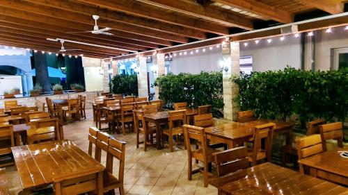 Villa Palčić في نوفاليا: مطعم بطاولات خشبية وكراسي ونباتات