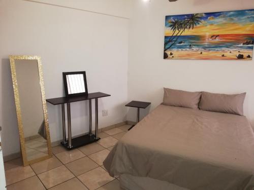 a bedroom with a bed and a painting on the wall at A Beach Condo in Durban