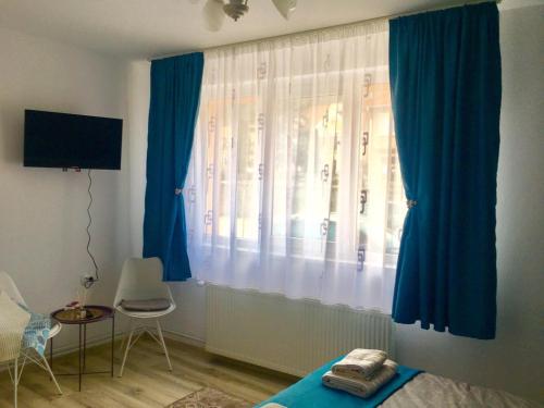 een slaapkamer met blauwe gordijnen en een bed en een tafel bij Lightning Vacation House in Sighişoara