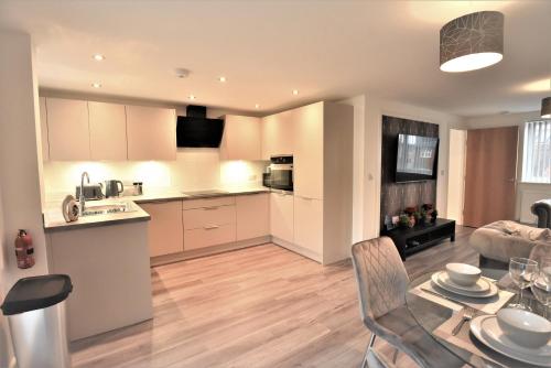 a kitchen and living room with a table and chairs at Exec 2Bed 2Bath Serviced Apartment Balcony Parking in Milton Keynes