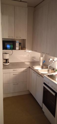 Biała kuchnia ze zlewem i kuchenką mikrofalową w obiekcie Merirauma Apartments w mieście Rauma