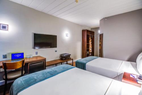 a hotel room with two beds and a desk and a tv at Cyan Resort by Atlantica in Itupeva