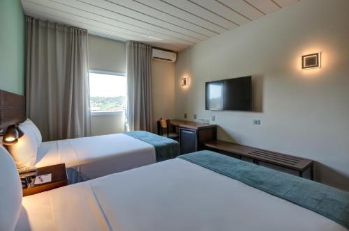 a hotel room with two beds and a flat screen tv at Cyan Resort by Atlantica in Itupeva