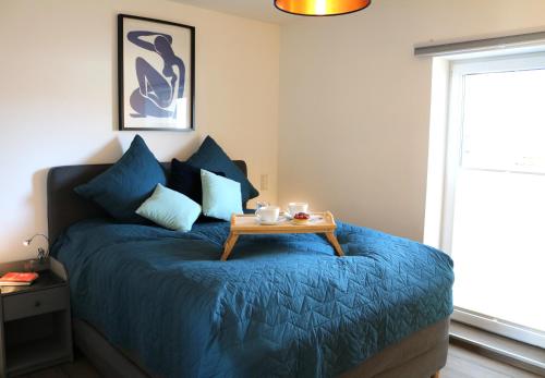 a bedroom with a blue bed with a table on it at Wohnung bei Façon in Eckernförde