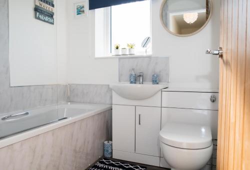 a bathroom with a tub and a toilet and a sink at Lovely 2-bedroom Seaside Retreat with Free Parking in Great Yarmouth