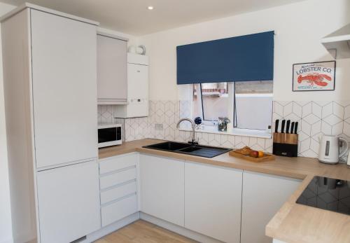 a kitchen with white cabinets and a counter top at Lovely 2-bedroom Seaside Retreat with Free Parking in Great Yarmouth