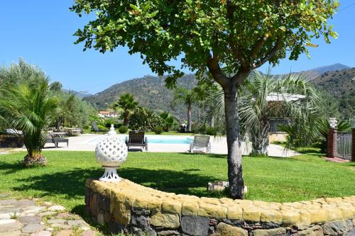 a vase sitting on a stone wall next to a tree at Taormina Villa Ibiscus Alcantara in Gaggi