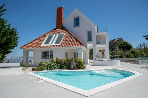 a villa with a swimming pool in front of a house at Cedros Nature House in Sintra