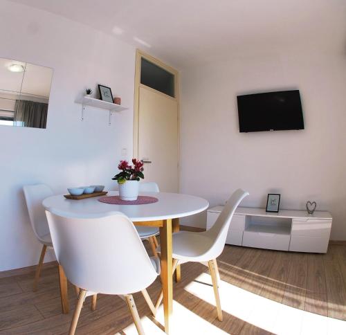a dining room with a table and white chairs at Apartmani Josipa in Baška Voda