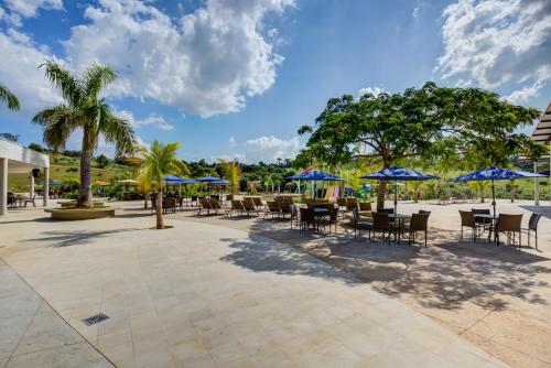 a patio with tables and chairs and blue umbrellas at Cyan Resort by Atlantica in Itupeva