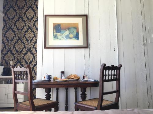 a table with two chairs and a picture on a wall at De kastanjehof 31 in Beerta