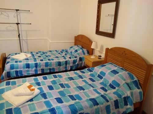 a bedroom with two beds and a mirror at Departamento Güemes in San Luis