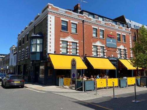 a large brick building with yellow umbrellas on a street at The White Star Tavern in Southampton