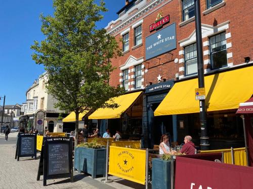 a street with people sitting at tables with yellow umbrellas at The White Star Tavern in Southampton