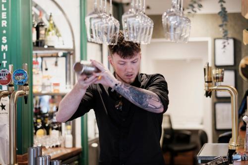 a man with a tattoo on his arm standing at a bar at The White Star Tavern in Southampton