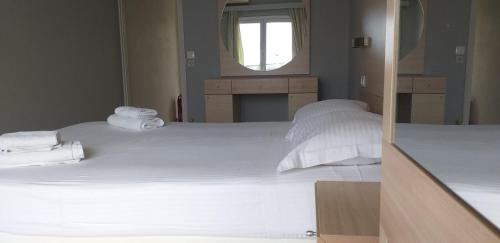 1 dormitorio con 2 camas con sábanas blancas y espejo en Alexandros Studios Moraitika en Moraitika