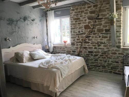 "La chambre des TISSERANDS" في Ménil-Hubert-sur-Orne: غرفة نوم بسرير وجدار من الطوب