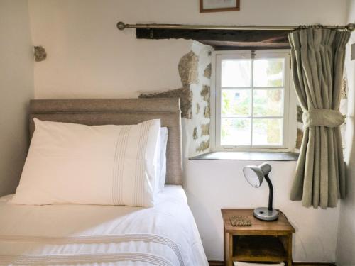 a bedroom with a bed and a window at Trevenning Barn in Bodmin