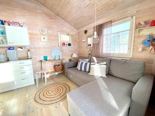 ein Wohnzimmer mit einem grauen Sofa und einer Küche in der Unterkunft Loistava Aurinkoranta Mökki in Ähtäri