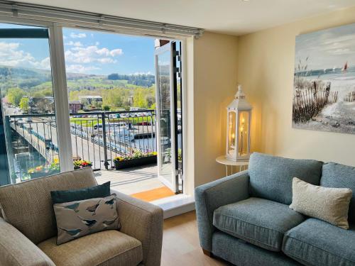 a living room with a couch and a large window at Riverside View Penthouse in Balloch, Loch Lomond in Balloch