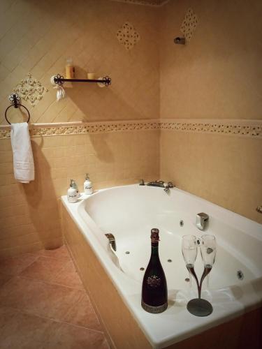 a bathroom with a bath tub with a bottle and wine glasses at Casa Pepe La Rosa Atico in Tolox