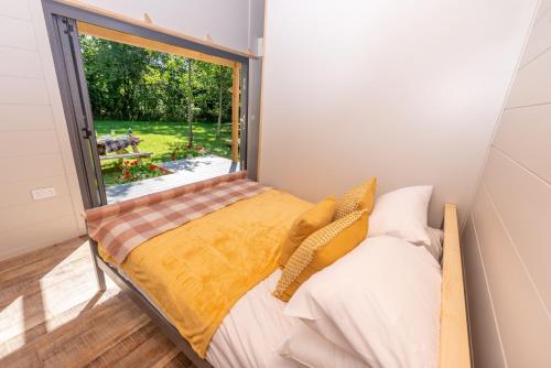 a small bedroom with a bed and a large window at Sunset Cabins at The Oaks Woodland Retreat in Barnstaple
