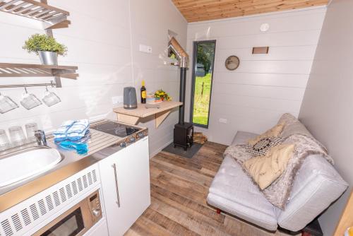 eine Küche mit Couch in einem winzigen Haus in der Unterkunft Sunset Cabins at The Oaks Woodland Retreat in Barnstaple