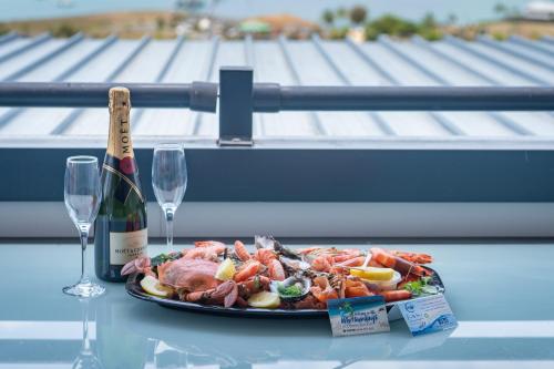 a plate of food with a bottle of wine and wine glasses at Ocean View Apartment 49 in Airlie Beach