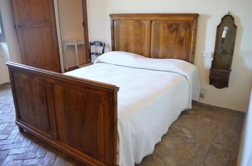 a bedroom with a large wooden bed with white sheets at Masseria Celentano Relais & Agriturismo in San Severo