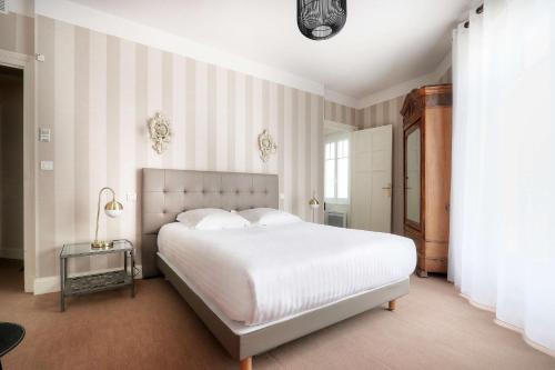 um quarto com uma grande cama branca com paredes listradas em Best Western Brittany La Baule Centre em La Baule