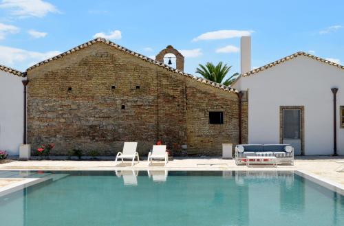 a pool with two lounge chairs and a brick building at Masseria Celentano Relais & Agriturismo in San Severo
