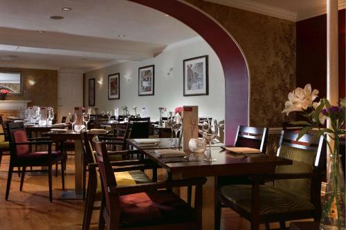 ドーチェスターにあるBest Western Wessex Royale Hotel Dorchesterの木製のテーブルと椅子と花のレストランを併設しています。