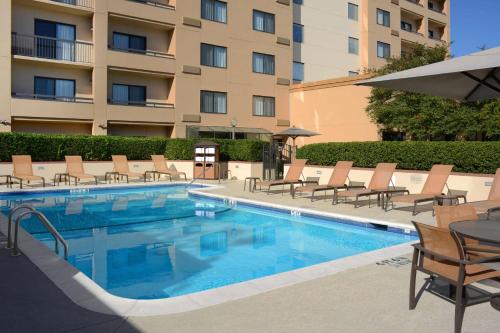 ein Pool mit Stühlen und ein Hotel in der Unterkunft Sonesta Select Dallas Central Expressway in Dallas