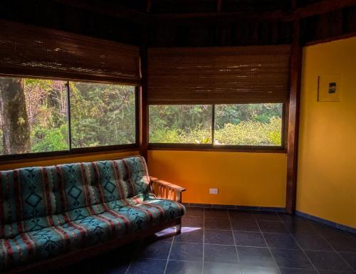 a living room with a couch and three windows at Hotel Vista de Olas in Santa Teresa Beach