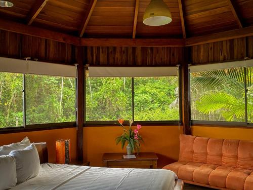 a bedroom with windows and a bed and a couch at Hotel Vista de Olas in Santa Teresa Beach