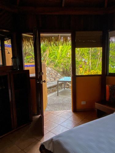 a bedroom with a bed and a door to a patio at Hotel Vista de Olas in Santa Teresa Beach