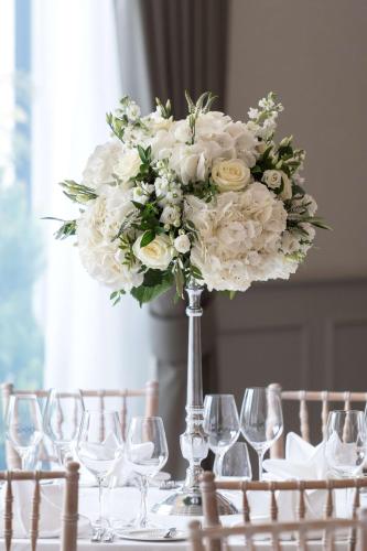 a vase filled with white flowers on a table with wine glasses at Ness Walk in Inverness